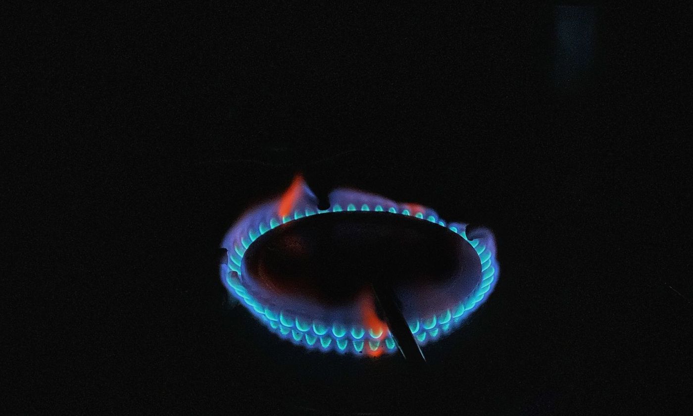 Small blue gas flame burning in a dark combustion chamber